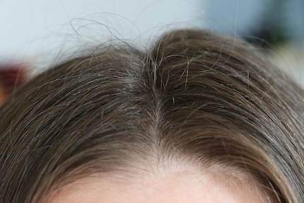 Pas encore coiffé. Les cheveux dépassent et la raie a un aspect différent de chaque côté.