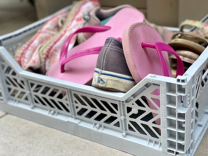 Une caisse contre la salade de chaussures devant la porte.