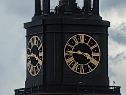 Fifty-fold zoom brings the church’s clock face into the picture, but it really doesn’t look pretty.
