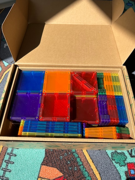 La boîte contient des plaques de construction de couleurs vives et de tailles différentes.