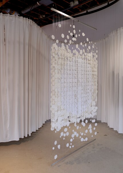 Le séparateur d'espace double face «Metamorphosis» se compose de cordes en acier inoxydable avec des formes en papier mobiles.