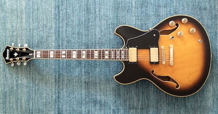 Une guitare semi-acoustique, reconnaissable à son grand corps avec ses ouïes en forme de F.