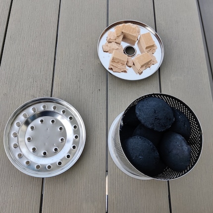 Le récipient pour le feu se compose du bac d'allumage, du récipient pour le charbon de bois et du couvercle correspondant. Veillez à ne pas mettre trop de briquettes dans le récipient.