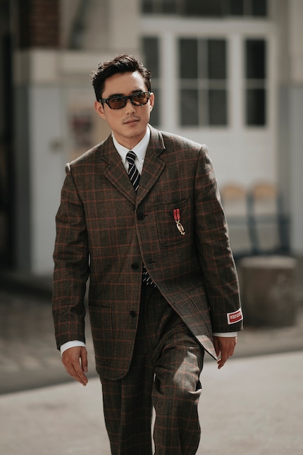 The checked suit and striped tie create a calm pattern mix.