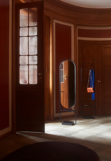 The mirror reflects the light from the brighter room into the darker space.
