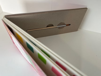 Un petit compartiment à pinceau (0,5 x 12 cm) est caché au dos du bloc.