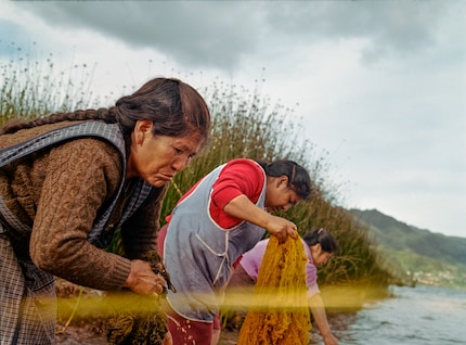 Two women washing freshly dyed fibres in the lake. Chemical dyes would release toxic substances into the water, but natural dyes blend seamlessly into the environment.