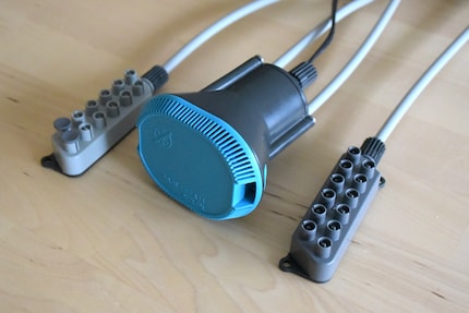 The pump (middle) is connected to distributor 1 (left) and distributor 2 (right) via hoses and threads. The third pump opening (middle cover between grey tubes) is closed.