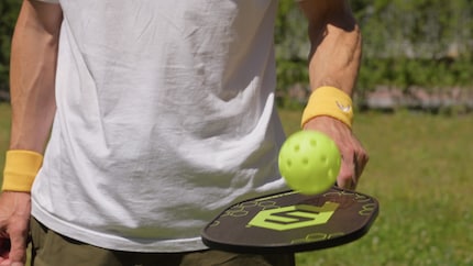 La partie pickleball du jeu : une raquette en bois, une balle en plastique.