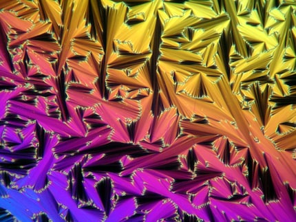 The molecules change their orientation, which reflects the light differently.